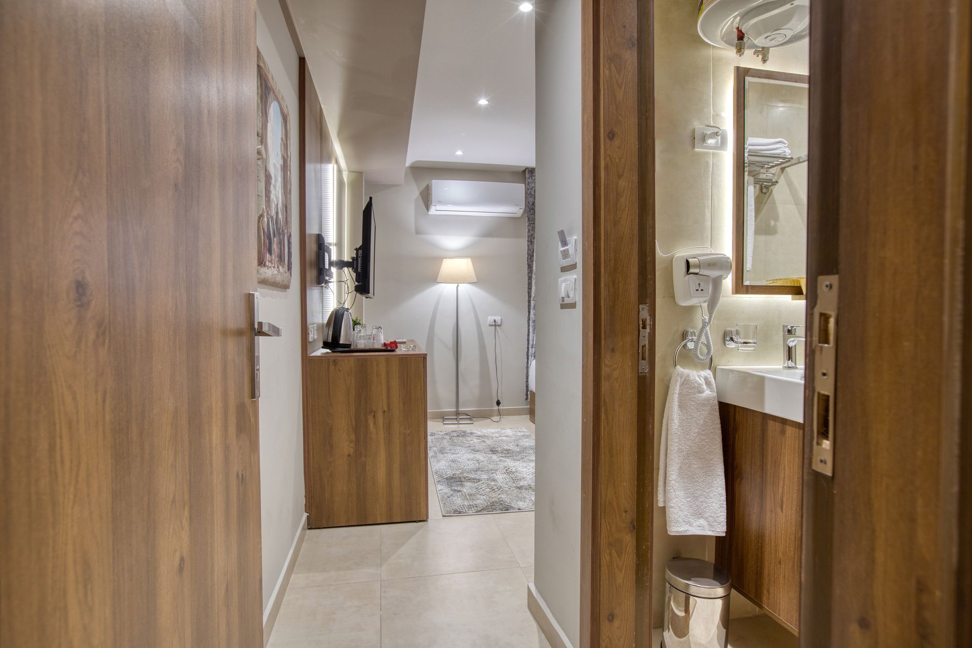 A hotel room with a wooden door leading to a bathroom.