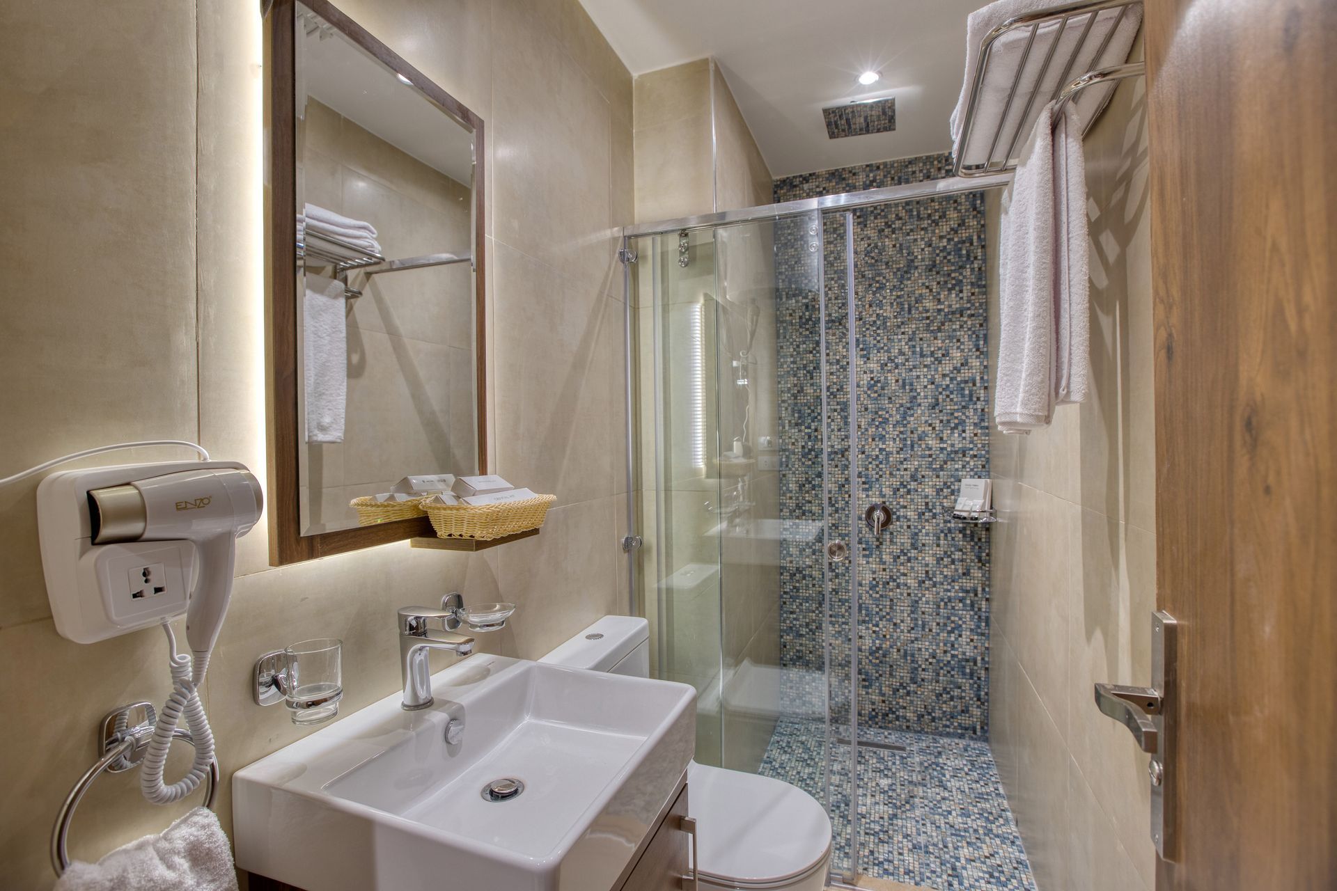 A bathroom with a sink , toilet , shower and mirror.