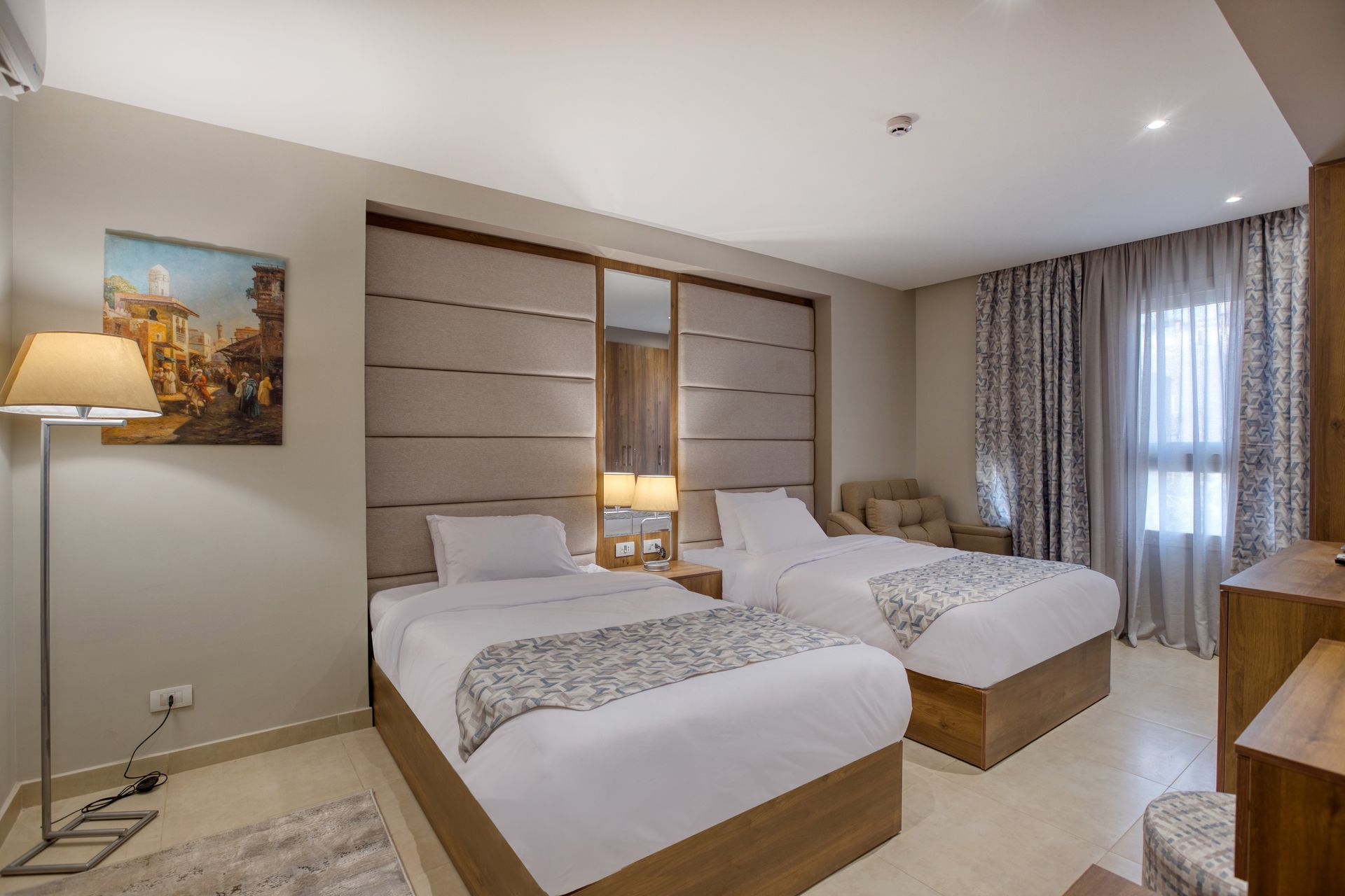 A hotel room with two beds and a painting on the wall.