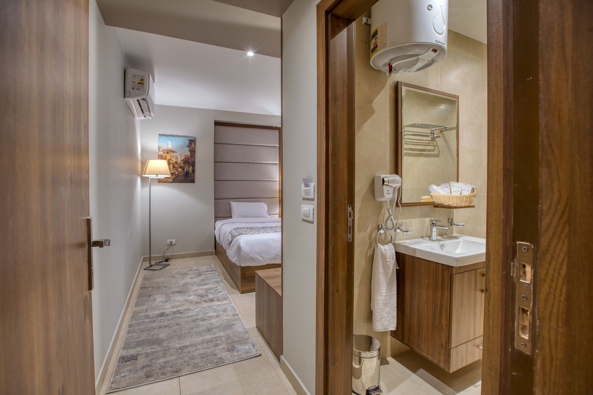 A hotel room with a bed , sink and mirror.