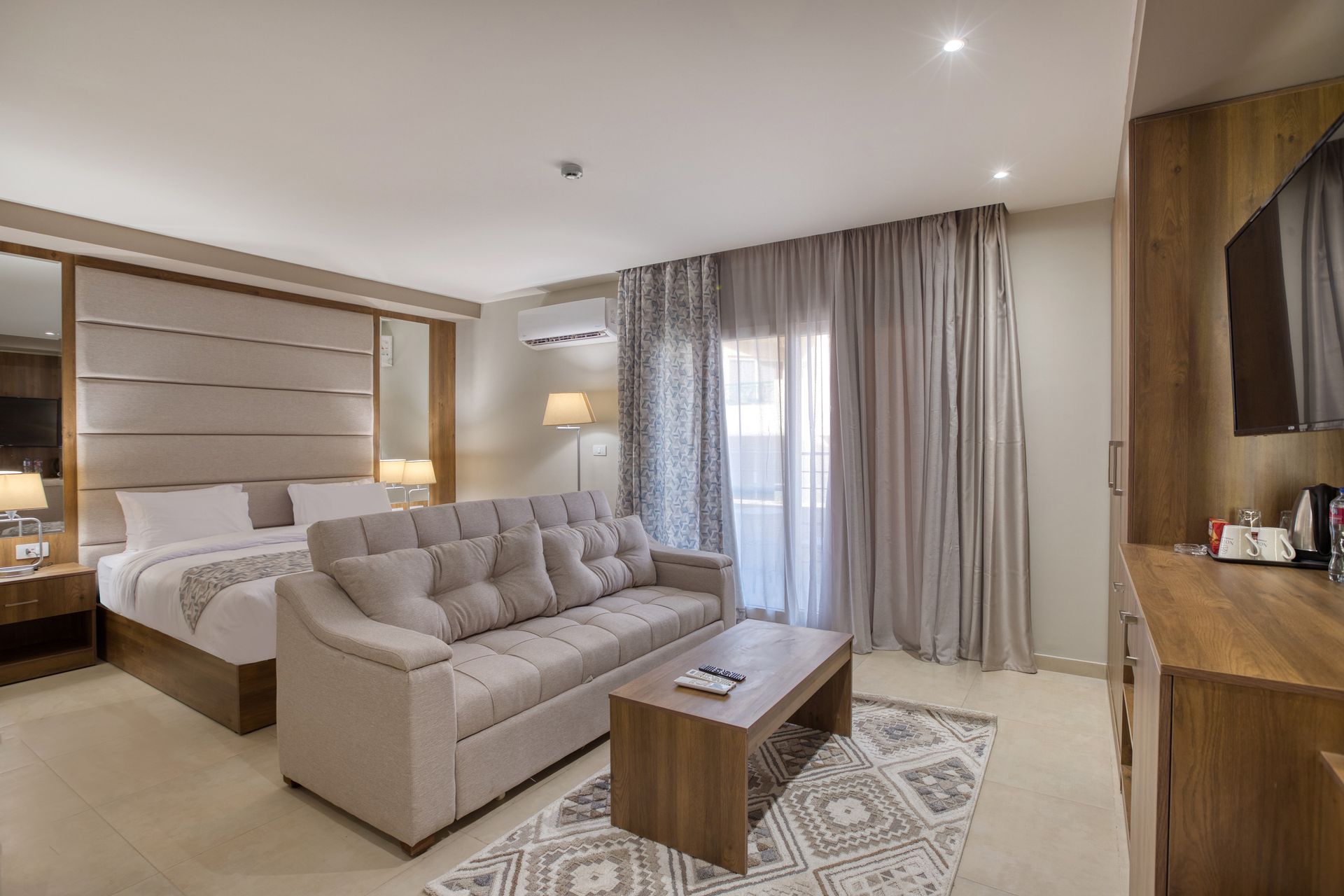 A hotel room with a bed , couch , coffee table and television.