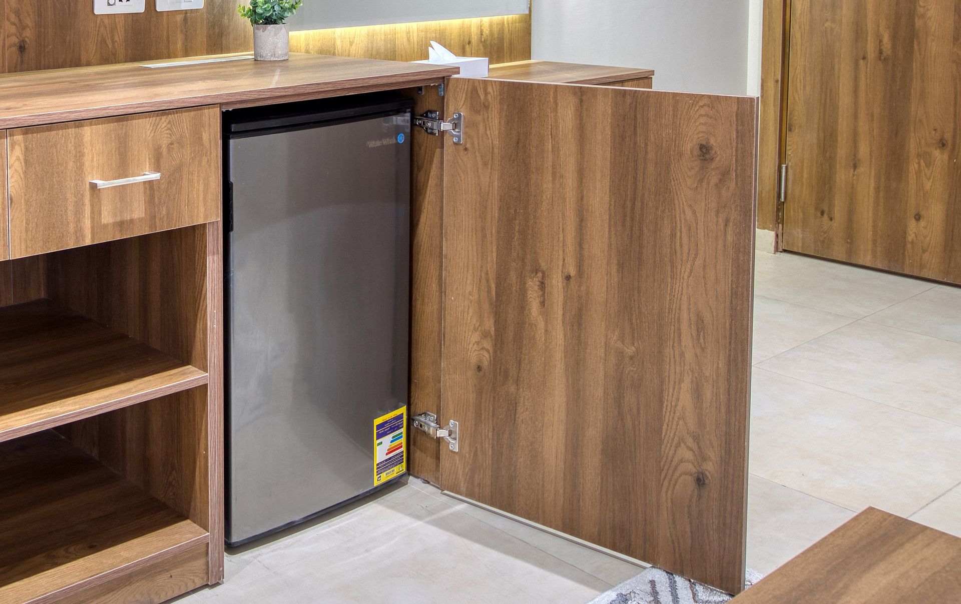 A stainless steel refrigerator is sitting inside of a wooden cabinet.