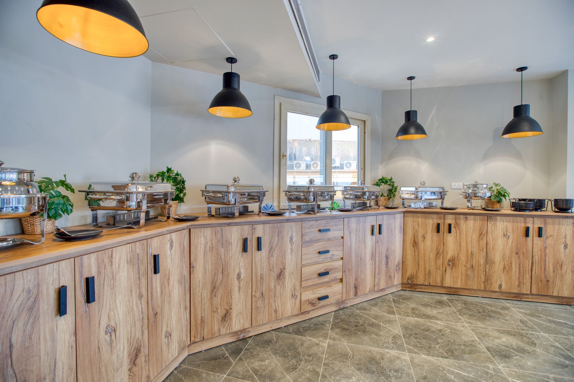 A buffet line in a restaurant with wooden cabinets and stainless steel buffet trays.