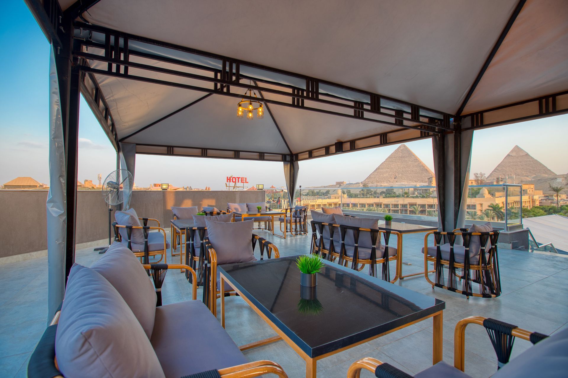 A patio with a table and chairs under a tent with pyramids in the background.