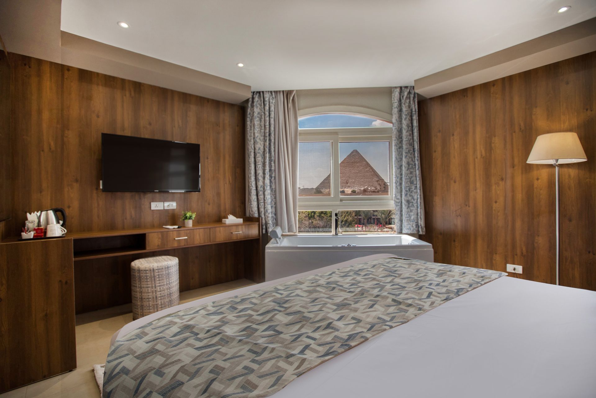 A hotel room with a pyramid in the background and a large bed.