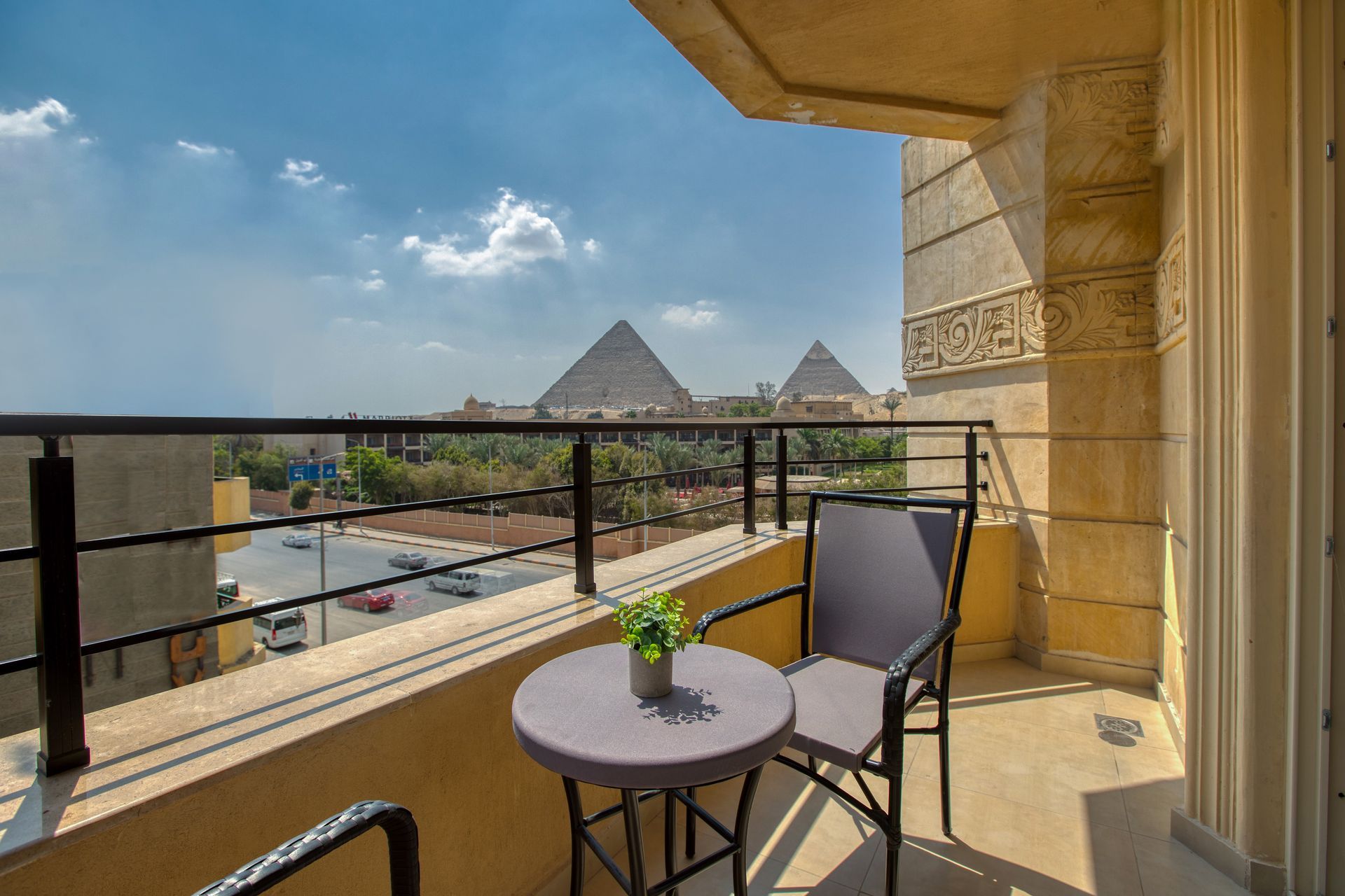A balcony with a table and chairs and a view of the pyramids.
