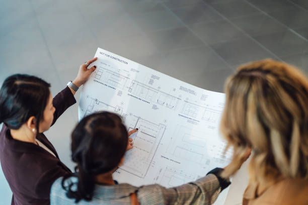 Three women are looking at a blueprint of a building.