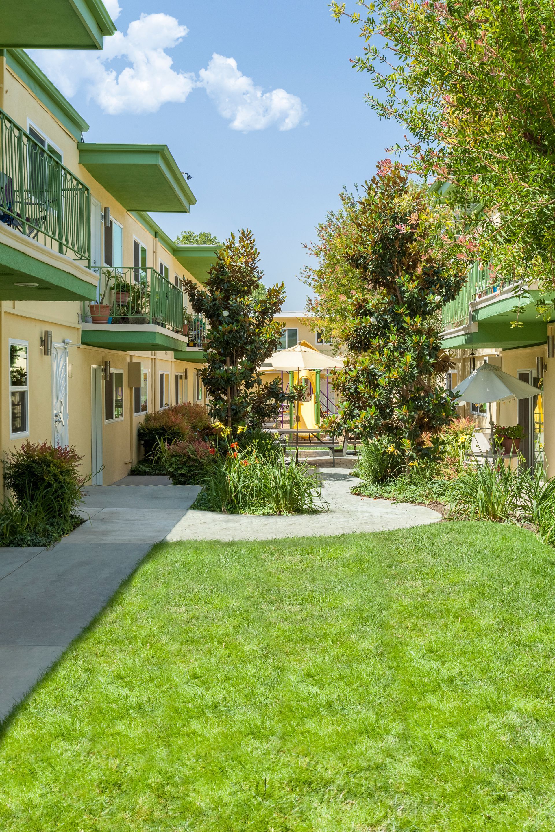 A row of apartment buildings with a lush green lawn between them.