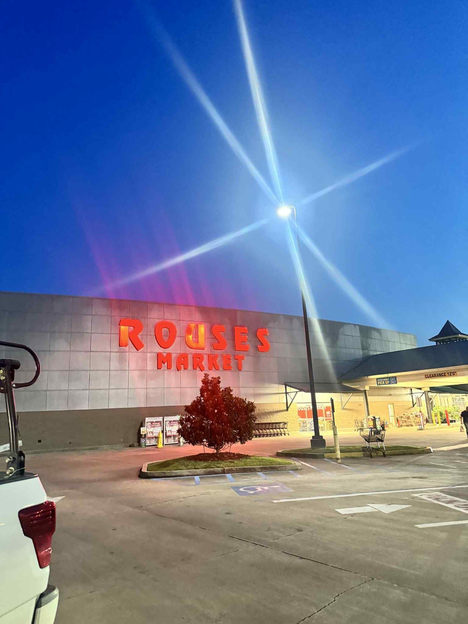 Rouses Market store front at dusk with illuminated sign. Bright street light with starburst effect.