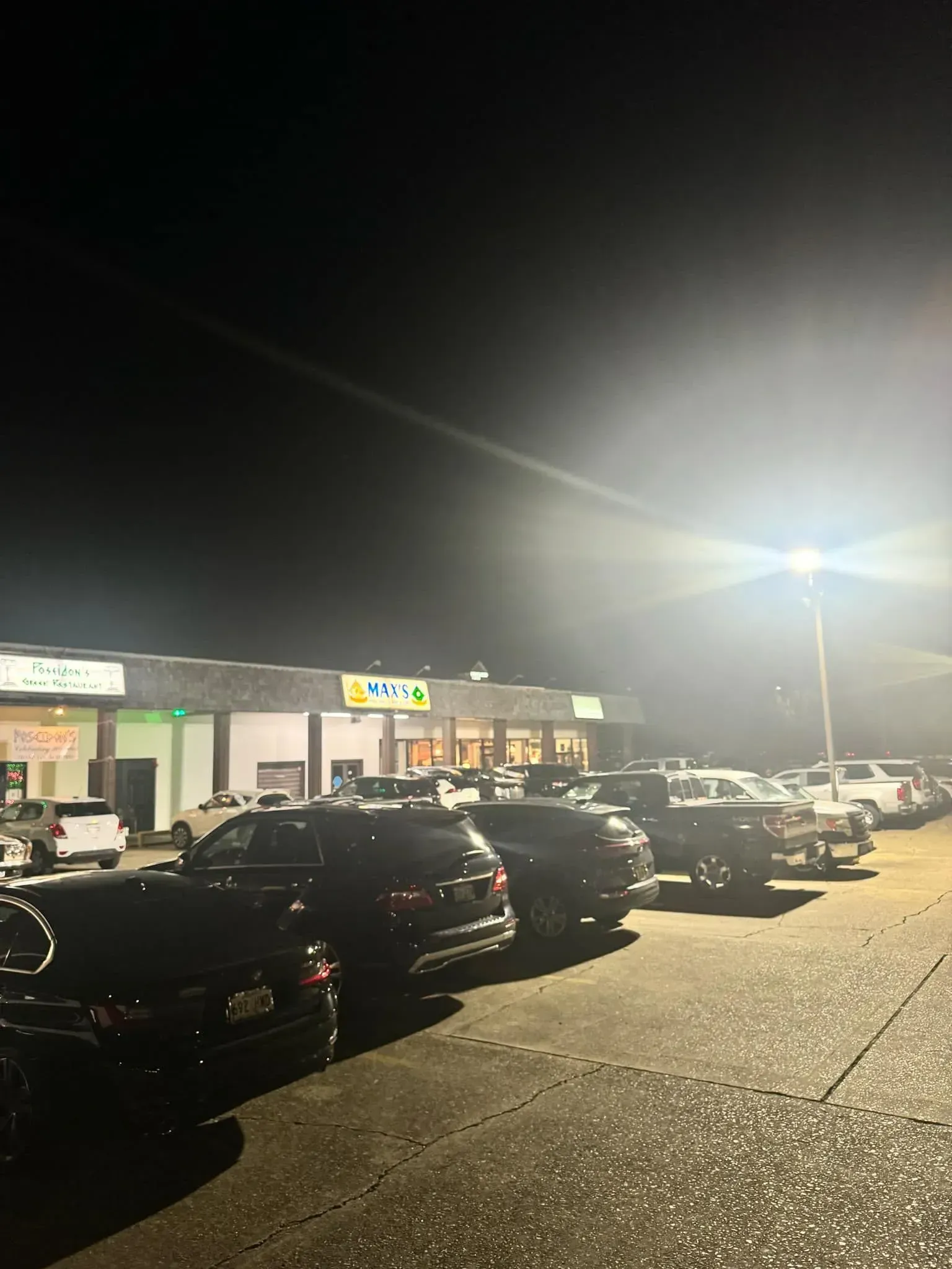 Cars parked in front of a brightly lit convenience store at night.