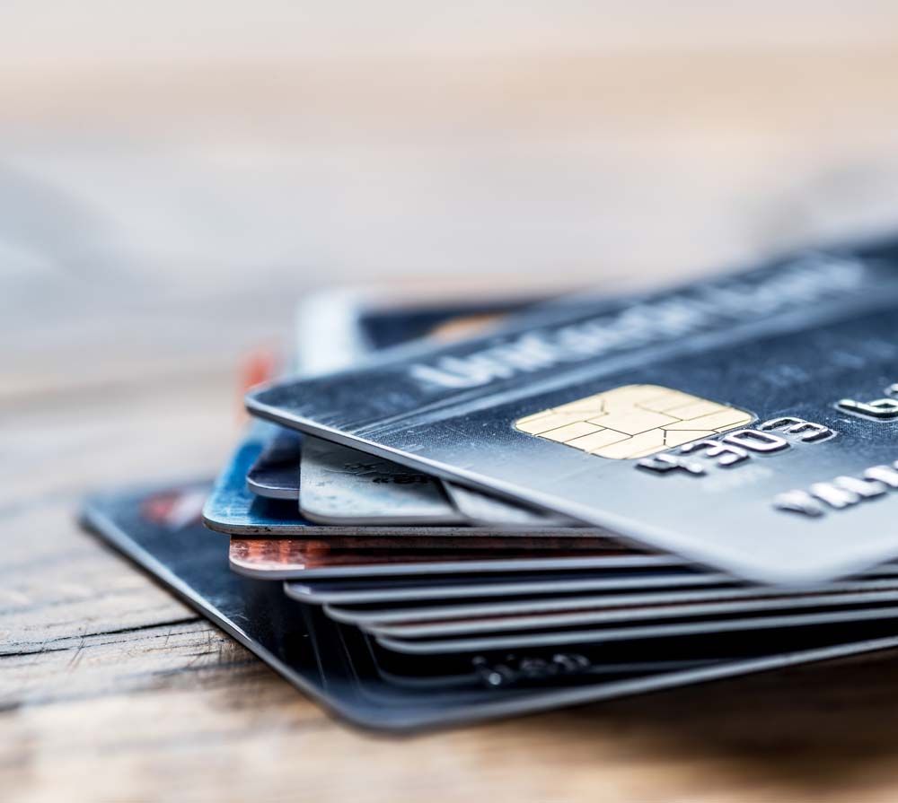 Stack of credit cards on a wooden surface, with a chip card in front.