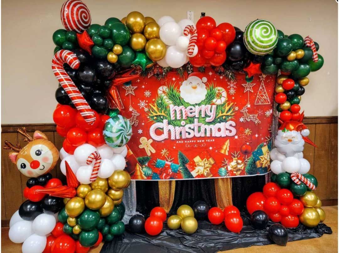 Christmas balloon arch framing a “Merry Christmas” sign with Santa, snowman, and festive red-green decorations
