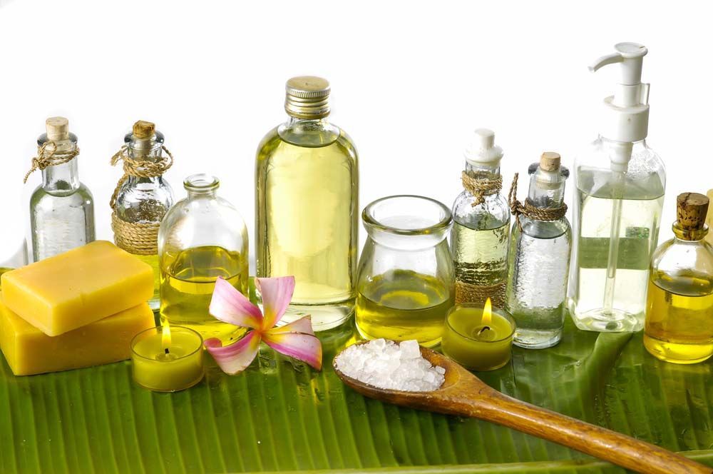 Spa oils, soaps, and bath salts arranged on a green leaf with a flower blossom