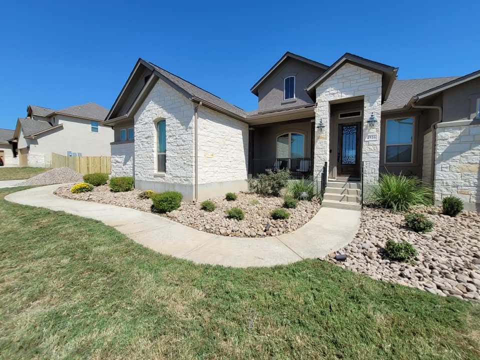 Modern suburban house exterior with stone siding, front porch, and landscaped walkway under a clear blue sky