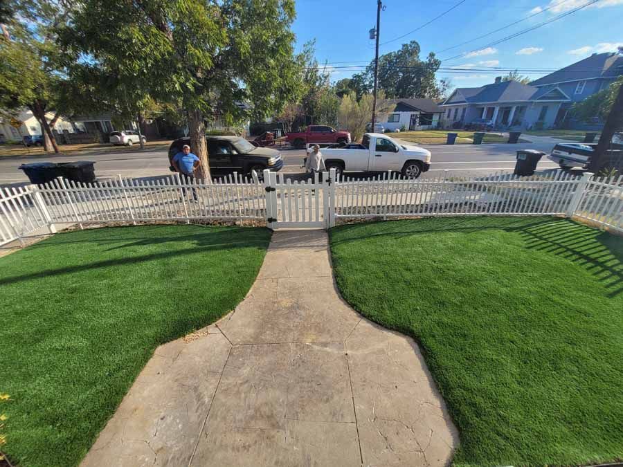 Front walkway to a white picket fence and suburban street with a white truck parked outside