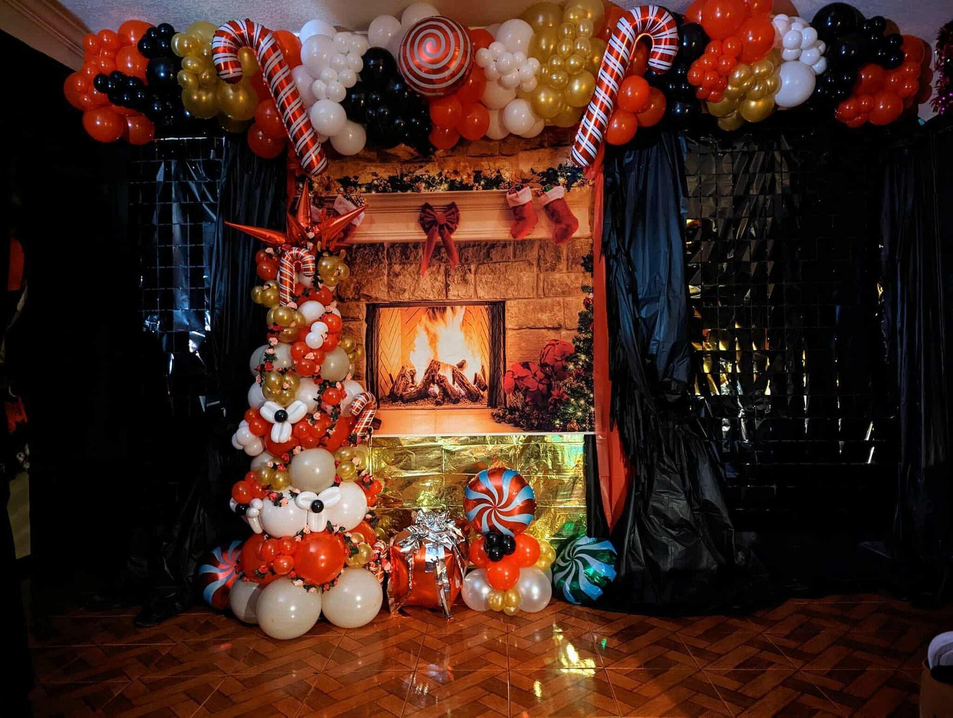 Halloween-themed fireplace display with black, orange, and white balloon garlands and glowing spooky decor