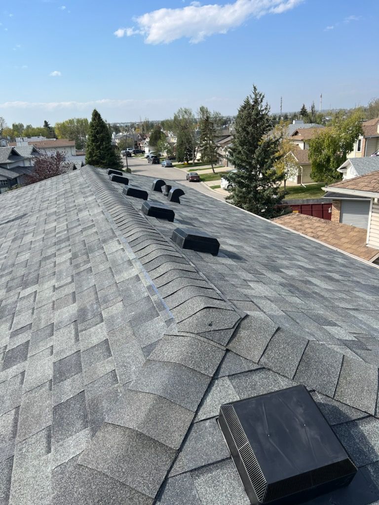 A roof with a lot of vents on it in a residential area.