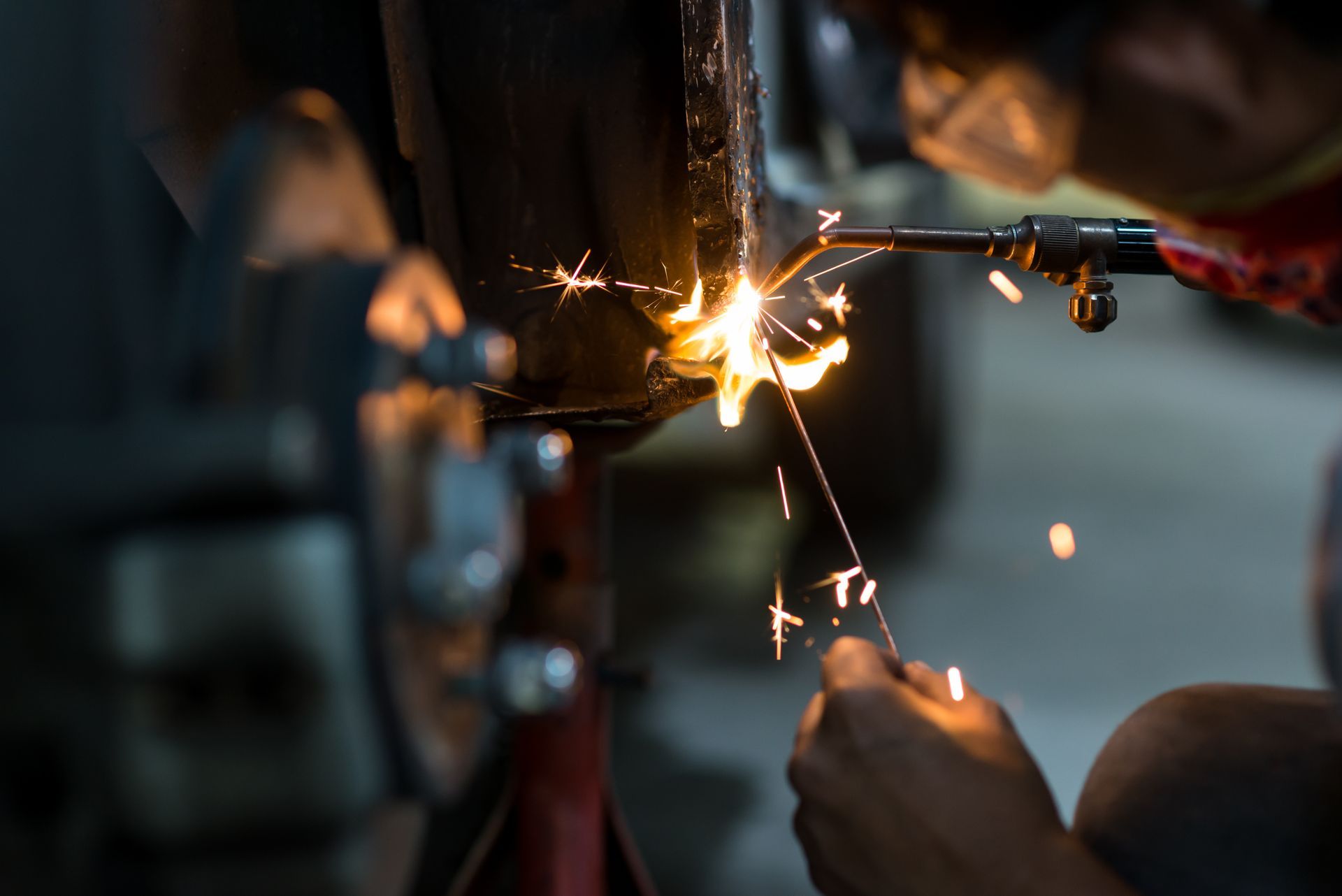 Person welding metal with bright sparks in a dark workshop