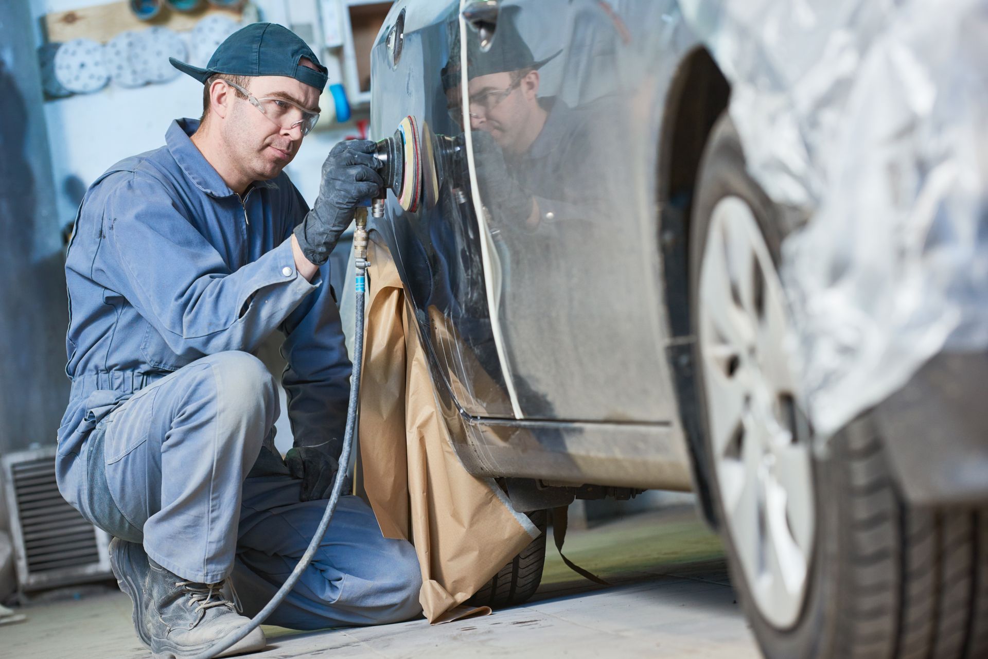 Auto body technician polishing a vehicle door during collision repair in a workshop. Auto body technician polishing a vehicle door during collision repair in a workshop.