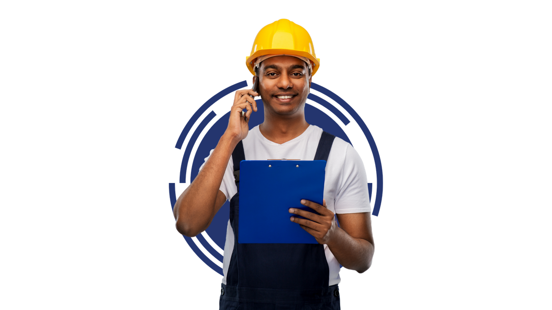A man in a hard hat is holding a clipboard and talking on a cell phone.