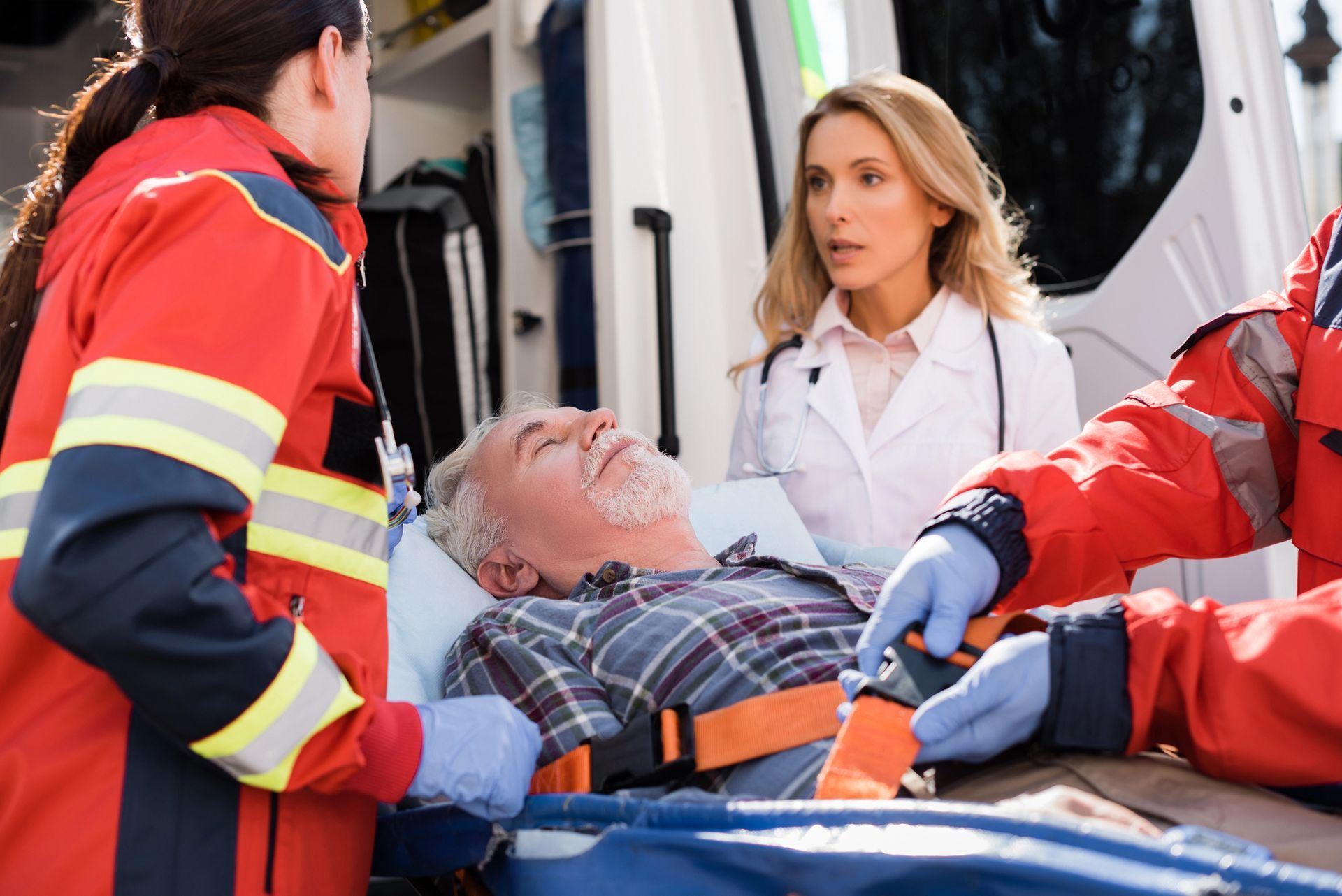 Paramedici che prestano soccorso a un uomo ferito su una barella accanto a un'ambulanza.