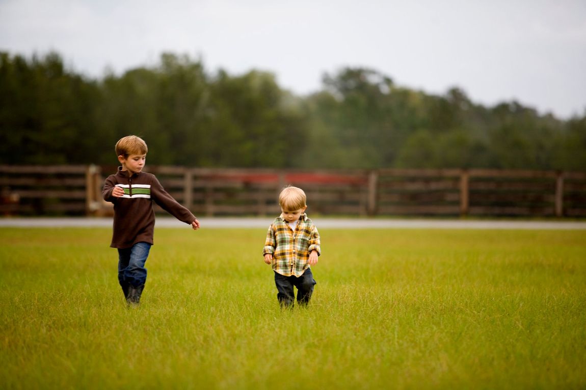 Two kids walking through a field