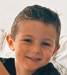 Boy with brown hair smiles, looking at the camera.