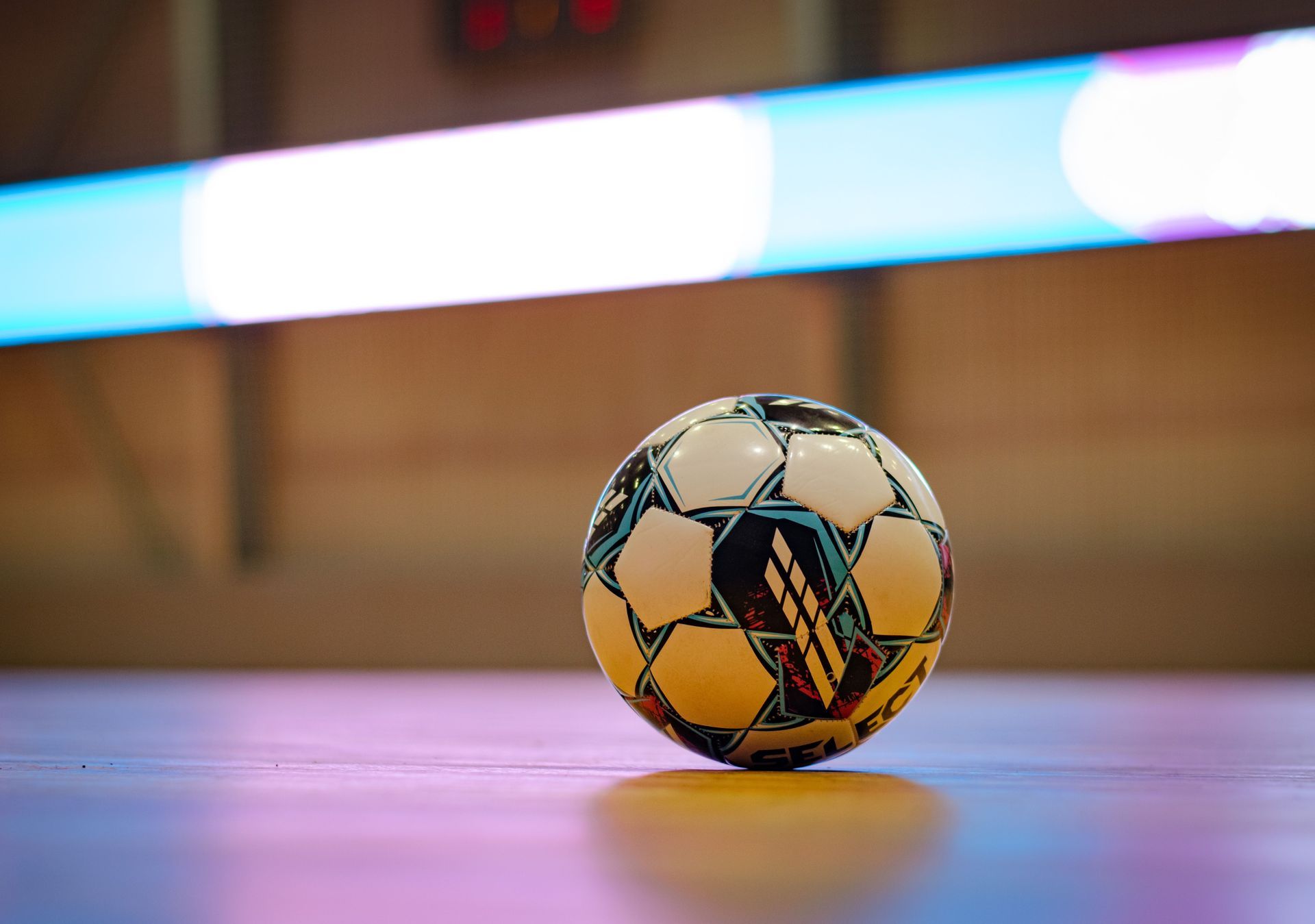 Soccer ball on green artificial turf next to a white line.