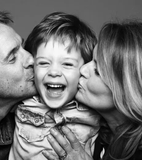 Parents kissing their laughing young son on the cheeks, family dentistry near Southampton