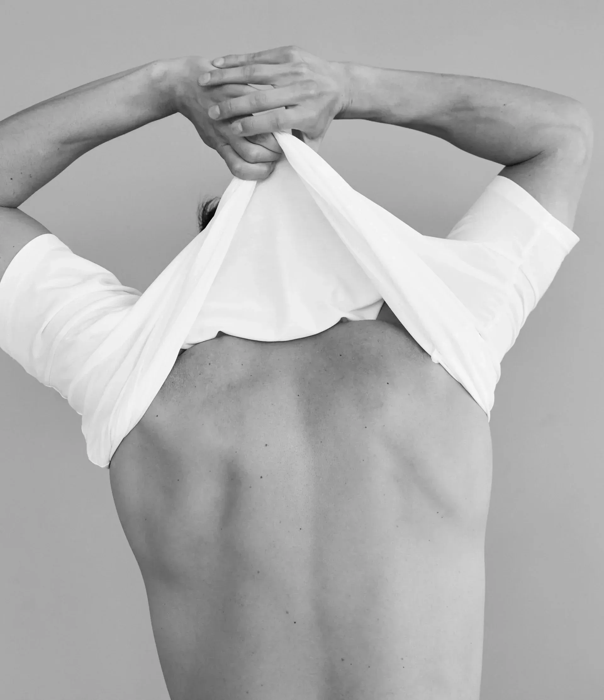 Person removing a white t-shirt, illustrating hyperhidrosis treatment at ORION Dental near Southampton