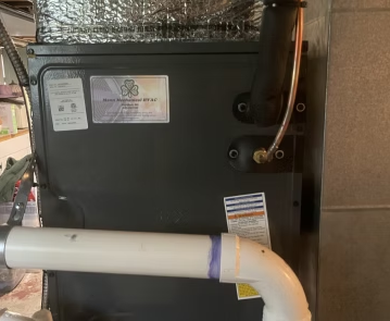 Black HVAC unit with copper pipes and a white insulated pipe in a utility space