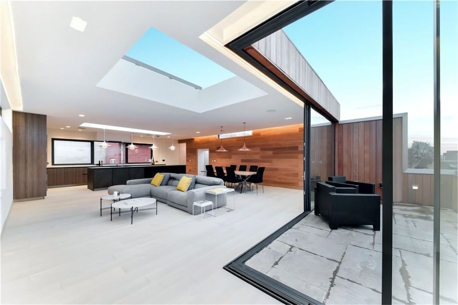 Modern open-plan living space with skylights, dining area, and patio access through a large sliding glass door.