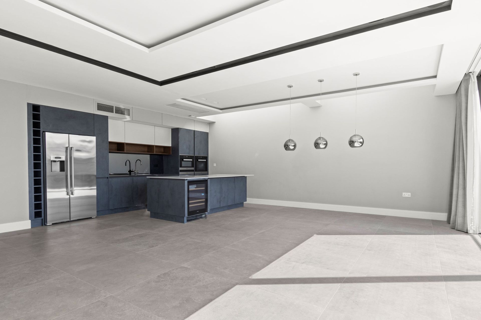 Modern kitchen with blue cabinets, stainless steel appliances, and pendant lights.
