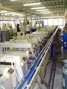 Interno di una fabbrica con numerosi serbatoi industriali, operai e attrezzature.