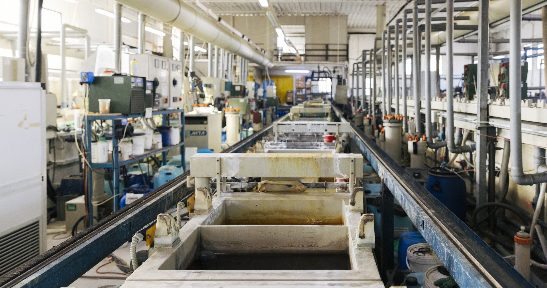 Impianto di placcatura industriale. Lunga fila di serbatoi chimici, macchinari sospesi e trasportatori.