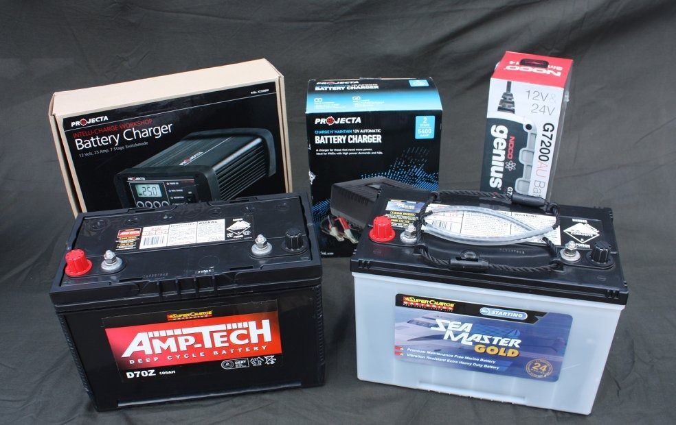 Three Batteries And A Battery Charger Are On A Table — Rainbow Beach Auto Electrics In Rainbow Beach, QLD
