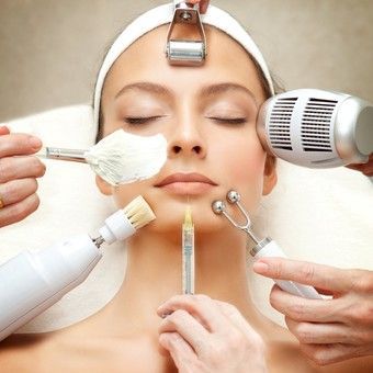 Mujer recibiendo tratamientos faciales, varias herramientas rodeando su rostro.