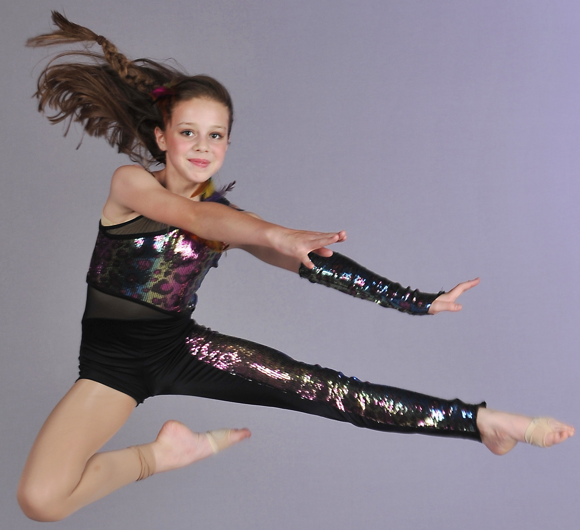 A young dancer is leaping in the air and striking a pose