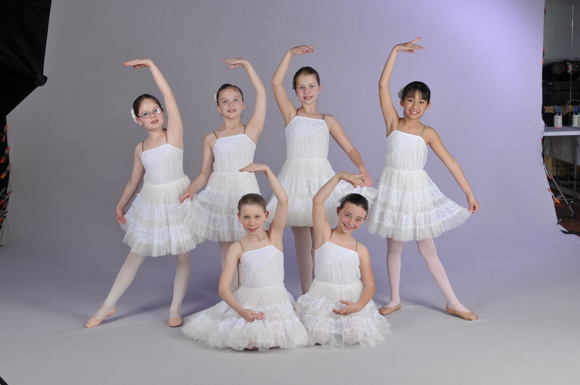 a group of young girls in white dresses are posing for a picture .