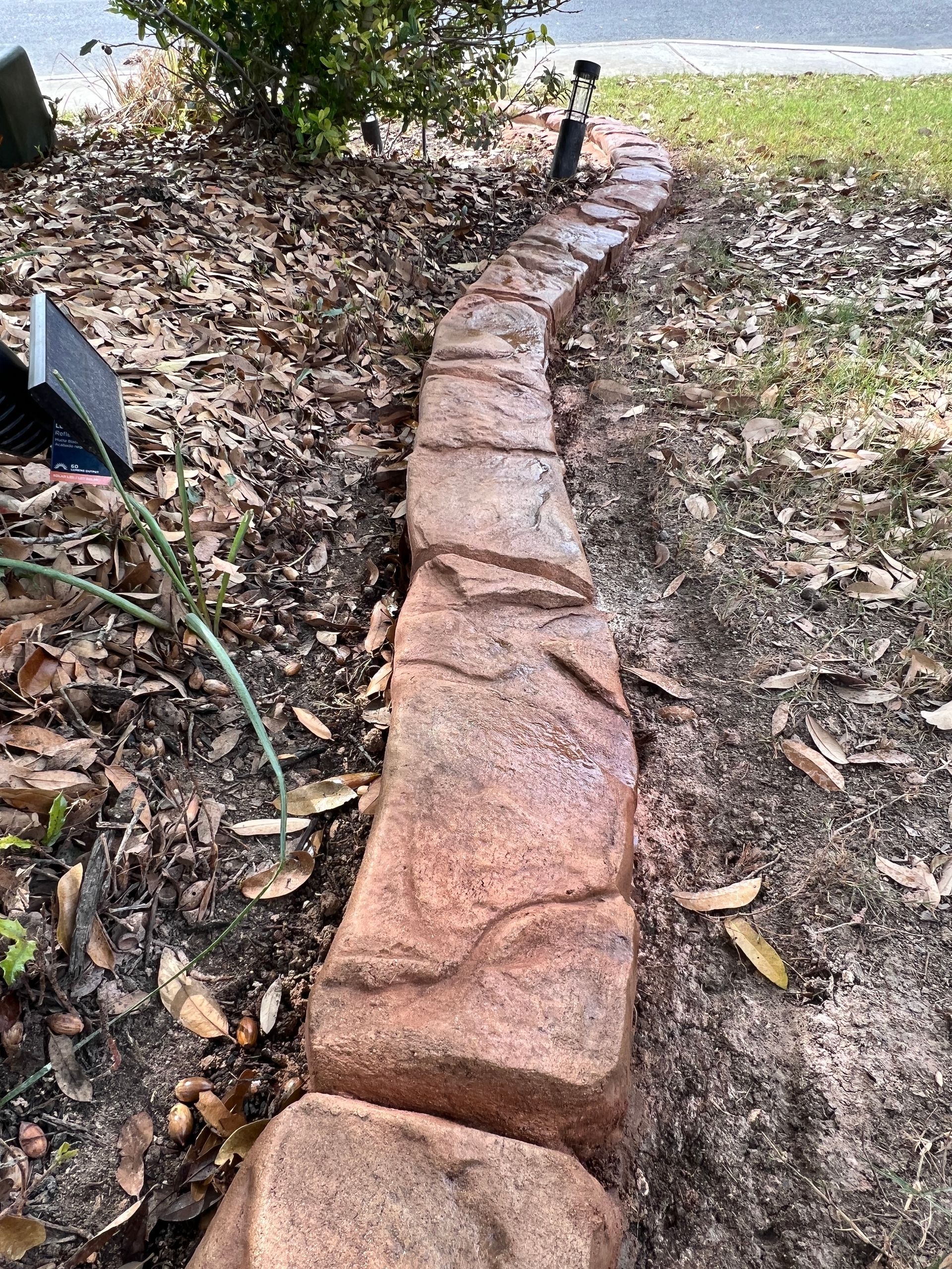 A stone walkway is being built in the middle of a yard.