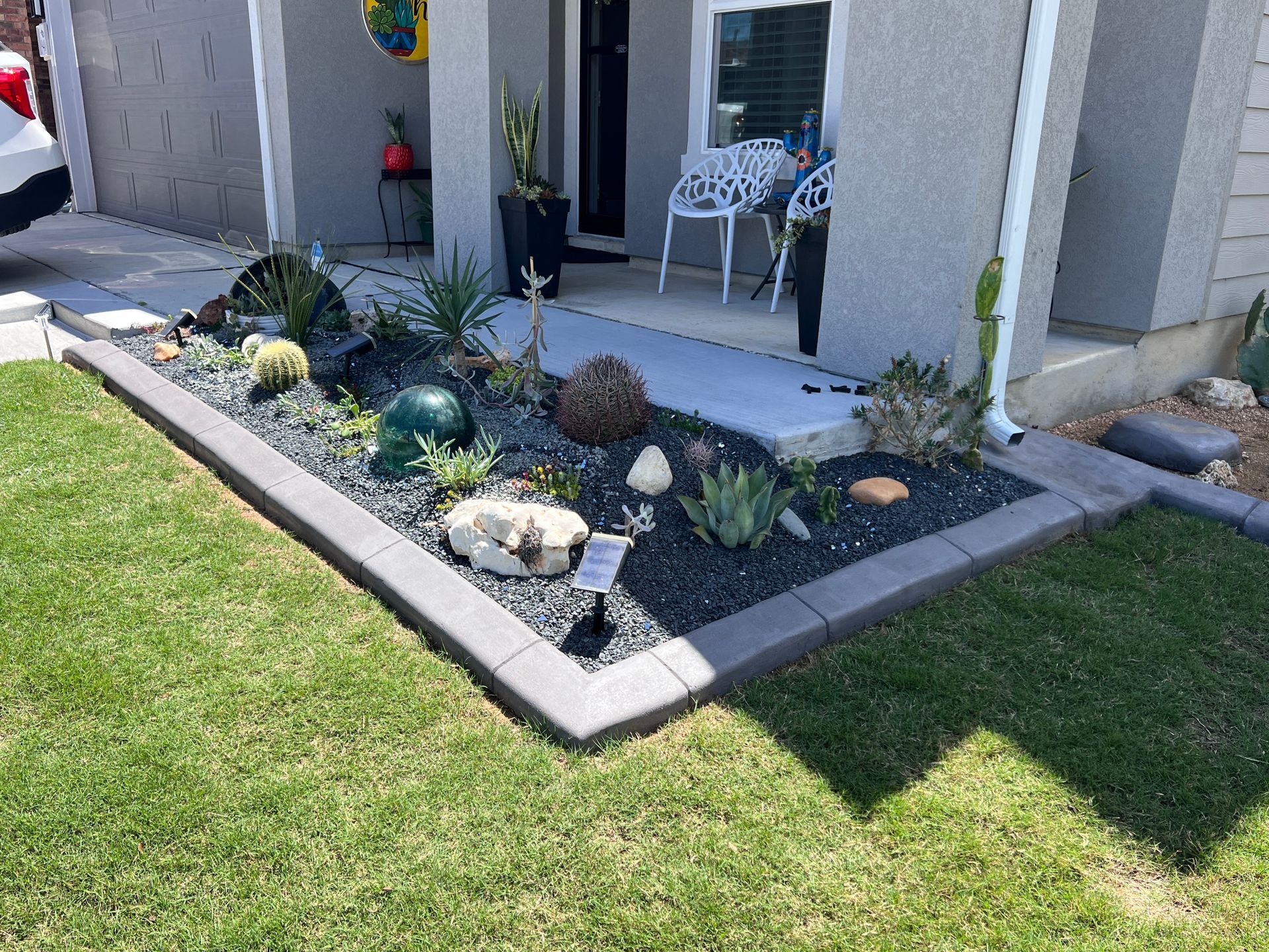 A car is parked in front of a house with a garden in front of it.