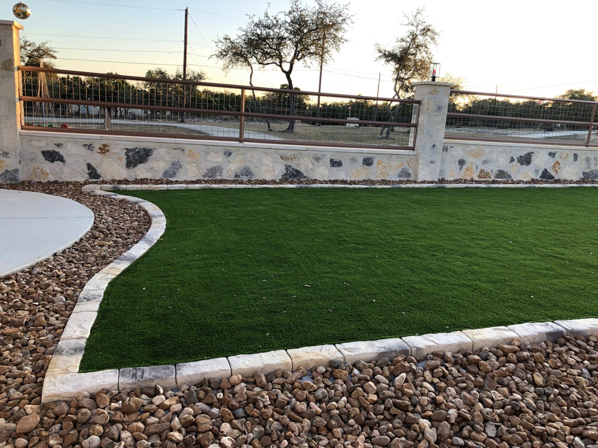 A lush green lawn with a stone wall in the background