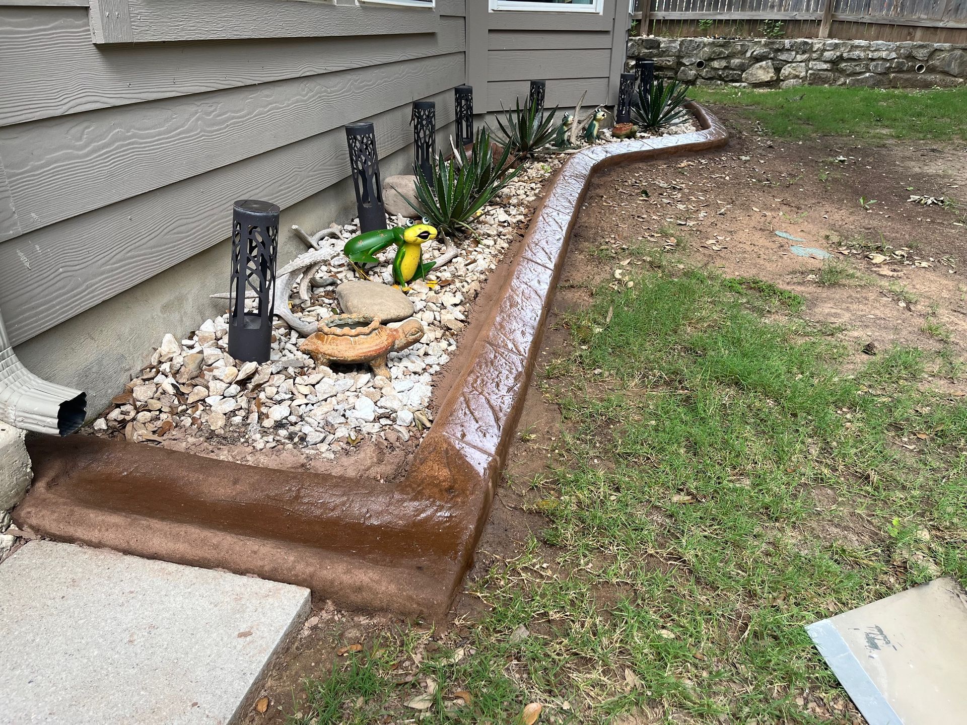 A concrete curb in a yard next to a house.