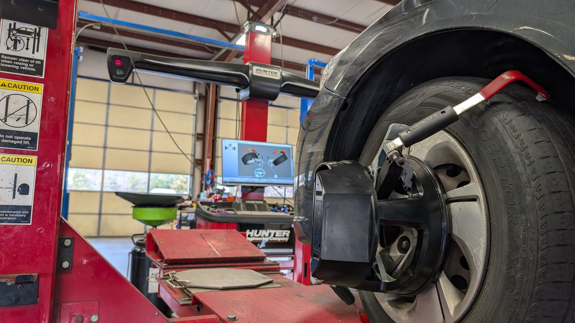 A car wheel mounted on a rack in an auto repair shop with a Hunter alignment sensor attached to the tire.