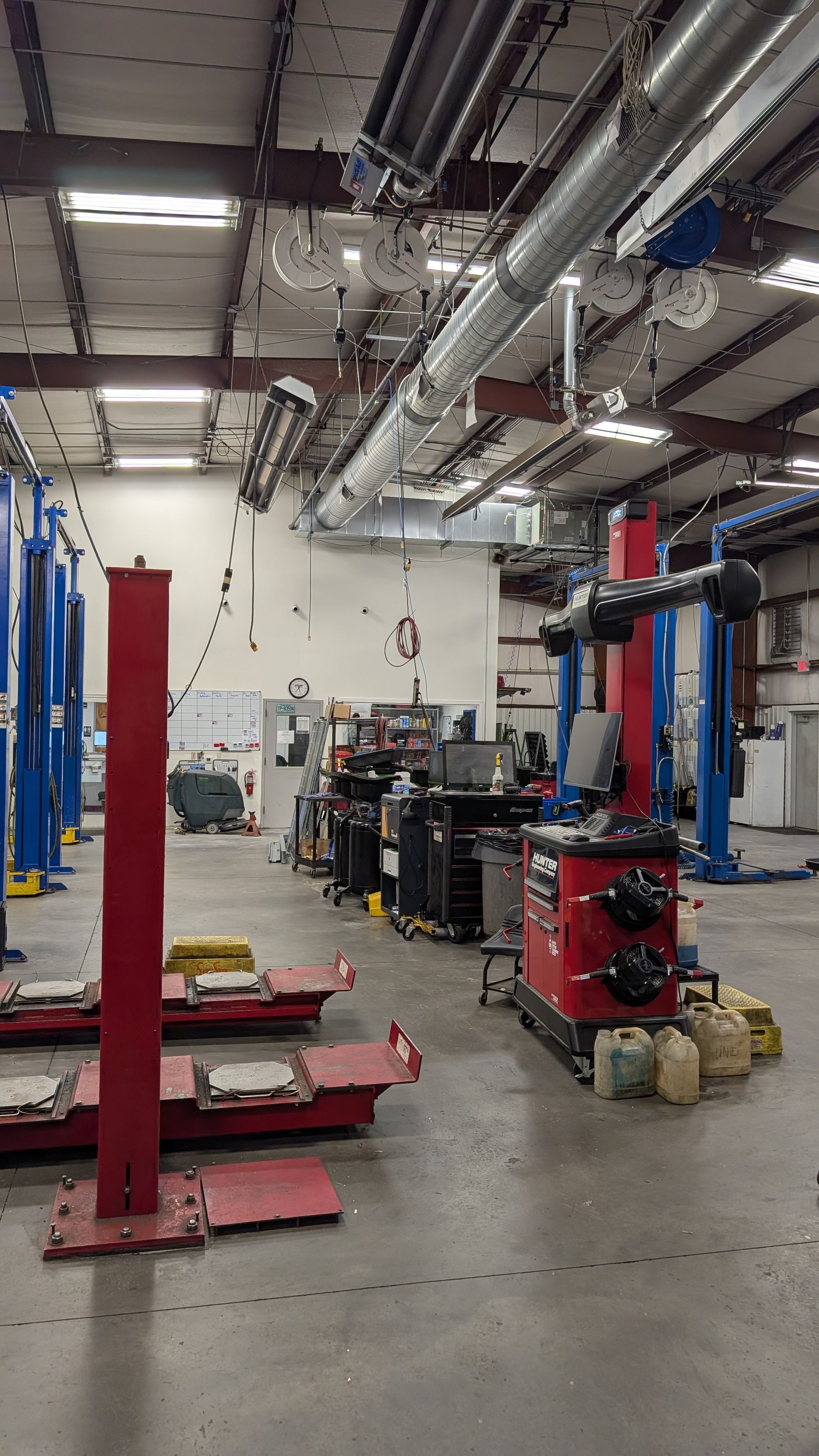 An auto repair shop interior featuring hydraulic lifts, a tire machine, and tool storage units on a concrete floor.