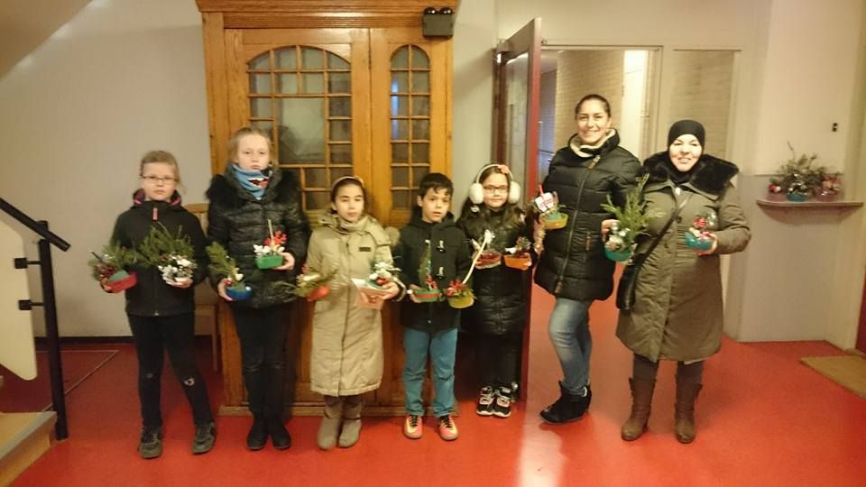 Zes mensen met kleine potplanten voor houten deuren binnenshuis.