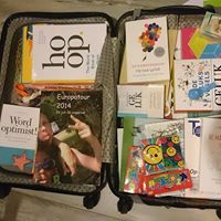 Open koffer met boeken en kleurrijke kaarten erin.