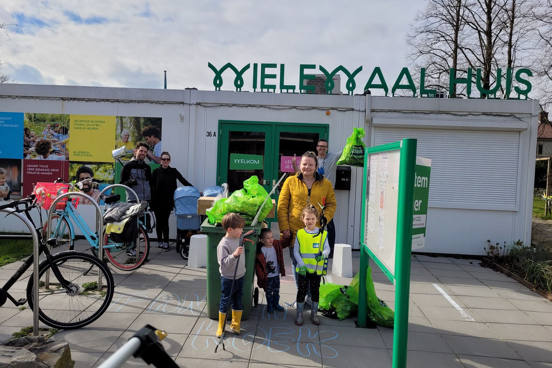 Mensen staan ​​voor een winkelpand met een groen uithangbord en een fiets die in de buurt geparkeerd staat.