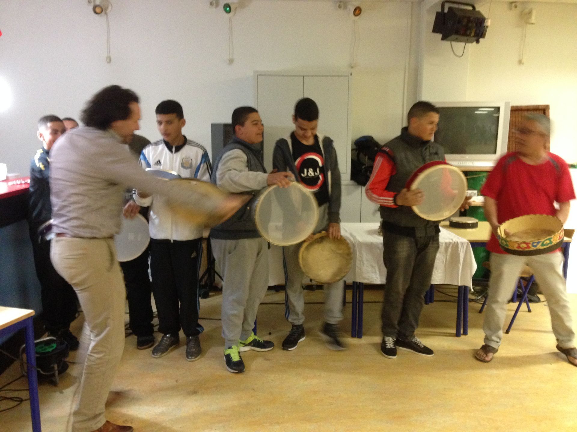 Mensen spelen drums in een kamer, met één persoon die ervoor danst.