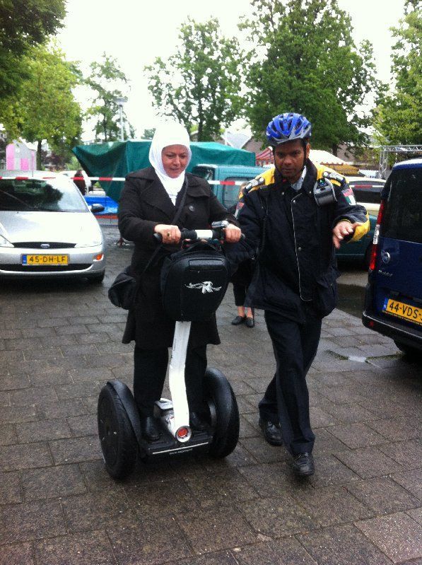 Twee mensen rijden op een Segway op een natte straat
